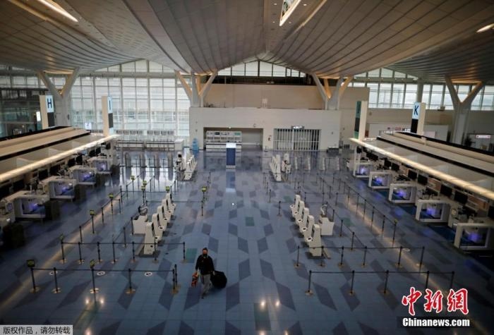 資料圖：日本東京，東京國(guó)際機(jī)場(chǎng)，一名乘客在國(guó)際航班航站樓的登機(jī)區(qū)。