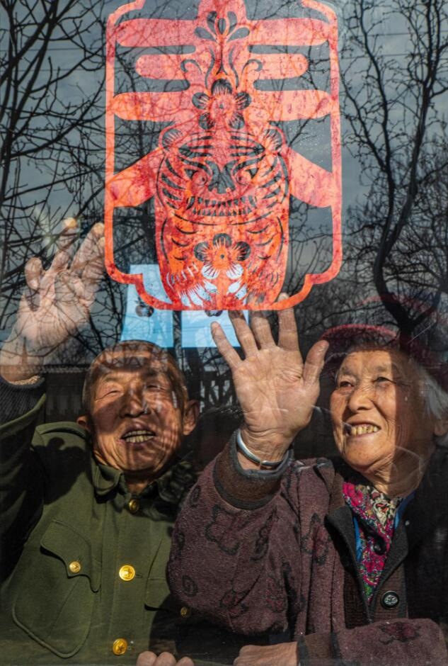 臘月里，霍州市師莊鄉(xiāng)馮南垣村村民師榮光(左)在災(zāi)后重建的新家里貼窗花。(霍州市委宣傳部供圖)