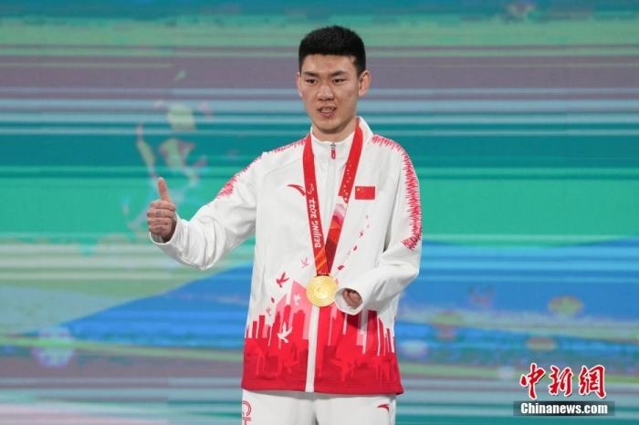 3月6日，梁景怡在延慶頒獎廣場領獎臺上豎起大拇指。當日，在國家高山滑雪中心舉行的北京2022年冬殘奧會殘奧高山滑雪男子超級大回轉—站姿決賽中，中國選手梁景怡奪得冠軍。 <a target='_blank' href='/'>中新社</a>記者 楊華峰 攝