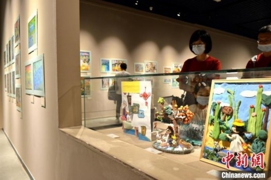 圖為家長(zhǎng)帶著孩子參觀展覽。呂明 攝