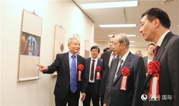 “湖州印象”攝影展主創(chuàng)、世界華人攝影協(xié)會副會長馮學敏向吳江浩大使、福田康夫前首相等嘉賓介紹展出作品。（人民網(wǎng) 許可攝）