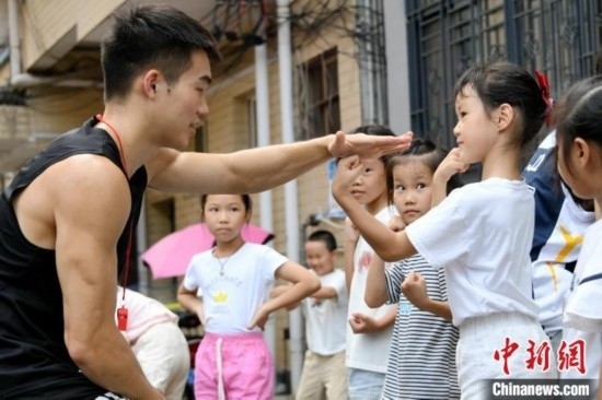 圖為大學(xué)生志愿者在組織孩子們參加體育健身活動。廖光福 攝