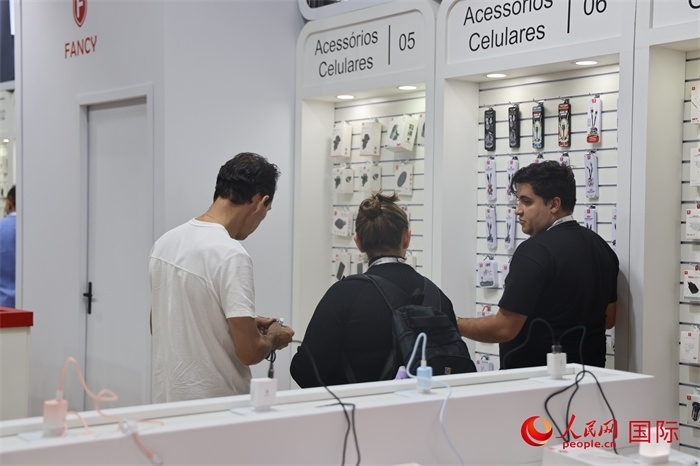 幾名參觀者在一個展臺前了解手機(jī)配件。（人民網(wǎng)記者 時(shí)元皓攝）