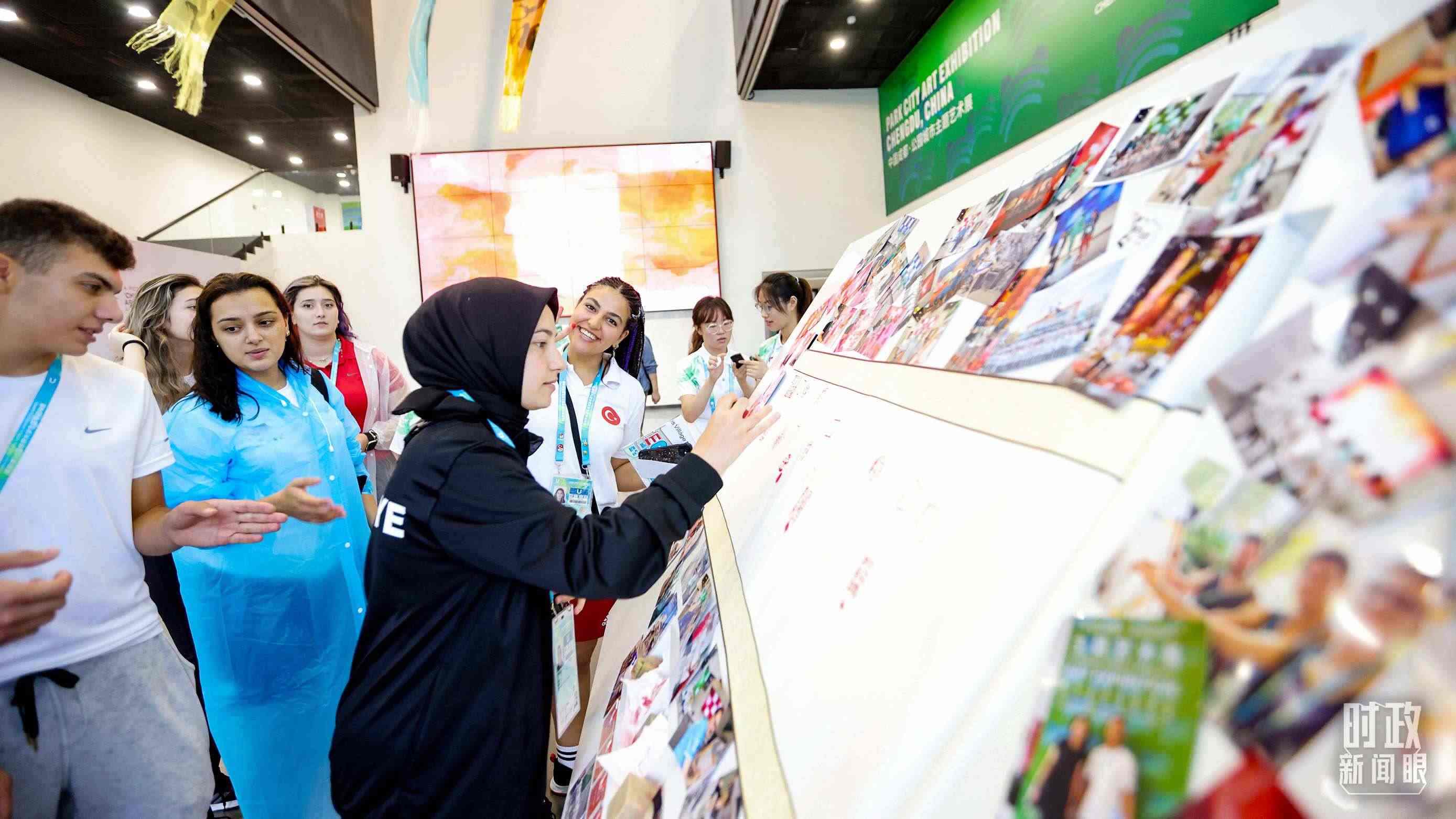 各國(guó)青年運(yùn)動(dòng)員正在參觀成都大運(yùn)村內(nèi)的“雪山下的公園城市，煙火里的幸福成都”主題藝術(shù)展。（總臺(tái)央視記者魏幫軍拍攝）