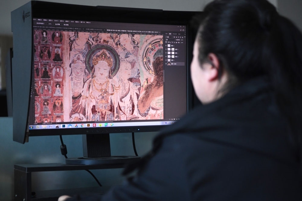 敦煌研究院文物數(shù)字化保護(hù)團(tuán)隊(duì)圖像處理人員年海麗在拼接壁畫圖像（2023年4月25日攝）。數(shù)字化探索為莫高窟的保護(hù)與傳承開辟了全新路徑，數(shù)字技術(shù)讓敦煌文物走出洞窟，跨出國門，走向“永久保存、永續(xù)利用”。新華社記者 陳斌 攝