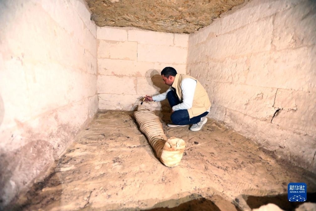 10月15日，在埃及明亞省考古現(xiàn)場，考古人員清理一座石鑿墓中的木乃伊。新華社發(fā)（艾哈邁德·戈馬攝）