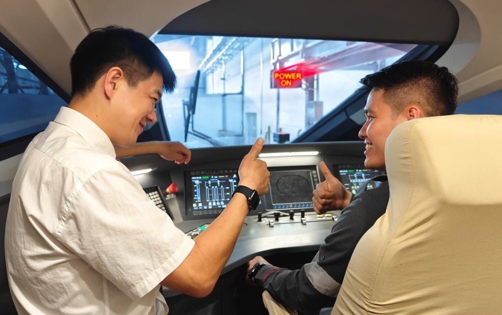 8月25日，在印度尼西亞萬隆的雅萬高鐵德卡魯爾動(dòng)車所內(nèi)，中國師傅穆振（左）在向印尼火車司機(jī)塞蒂亞萬講解動(dòng)車組出庫前的上電作業(yè)。