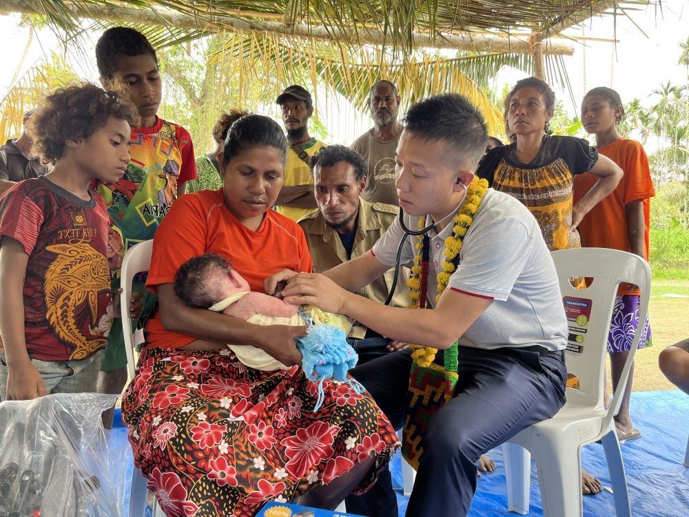 2023年8月5日，在巴布亞新幾內(nèi)亞中央省的一個村莊里，第12批援巴新中國醫(yī)療隊副隊長、新生兒科副主任醫(yī)師劉振球為嬰兒泰樂聽診檢查。泰樂出生時患有重癥，一度生命垂危，經(jīng)過劉振球與當(dāng)?shù)蒯t(yī)護(hù)人員的救治最終痊愈。從2002年起，中國連續(xù)向巴新派出12批醫(yī)療隊，為提高巴新醫(yī)療衛(wèi)生水平作出積極貢獻(xiàn)。
