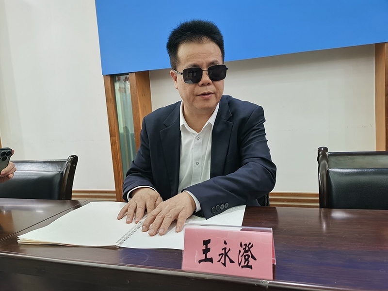 全國人大代表王永澄正在閱讀盲文版代表建議答復。本報記者 張 璁攝