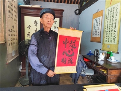 越南首都河內(nèi)文廟內(nèi)，阮明珠展示“中越心相近”書法作品。