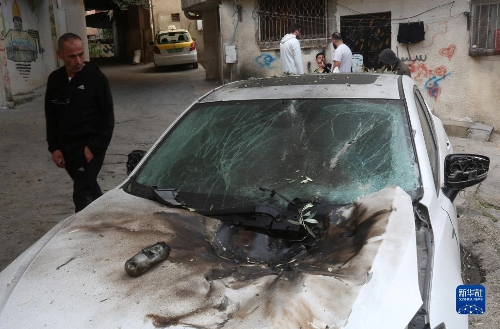 12月17日，在約旦河西岸城市圖勒凱爾姆附近的一處難民營，人們查看在沖突中損毀的車輛。新華社發(fā)（尼達爾·艾仕塔耶攝）