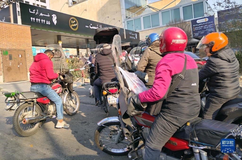 12月18日，摩托車(chē)在伊朗首都德黑蘭的一家加油站外等待加油。新華社記者 沙達(dá)提 攝