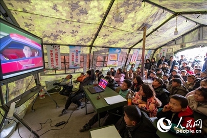 12月22日，在積石山縣大河家鎮(zhèn)大河村安置點(diǎn)，陸軍76集團(tuán)軍某旅搭建的“臨時學(xué)?！眱?nèi)，小朋友正在看動畫片。人民網(wǎng)記者 翁奇羽攝