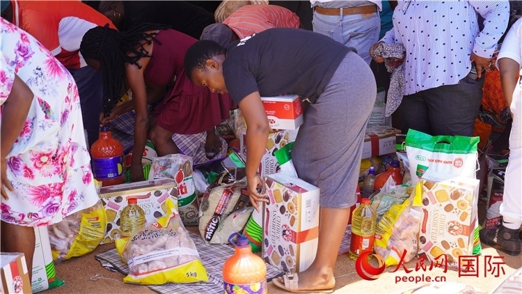 當(dāng)?shù)厣鐓^(qū)家庭領(lǐng)取物資。人民網(wǎng) 張茜攝