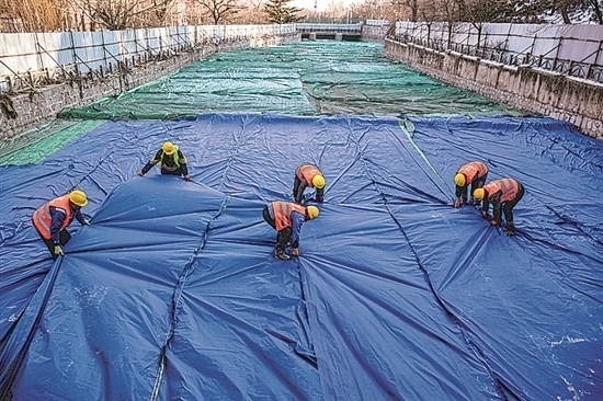 1月3日，房山區(qū)東風街道，工人正在修復的河道內給混凝土鋪設保溫布。