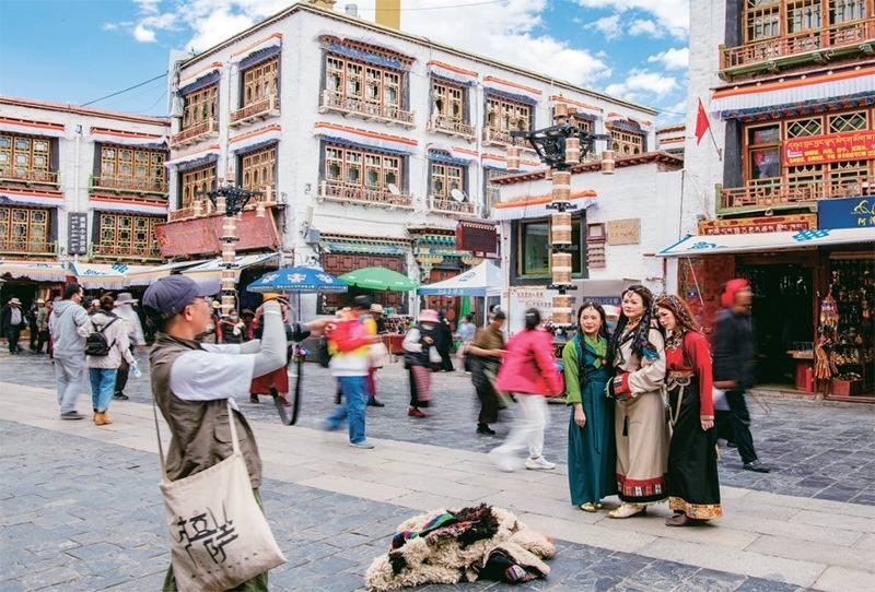 千年八廓街，見證民族團(tuán)結(jié)。2021年7月，習(xí)近平總書記來到位于西藏拉薩老城區(qū)的八廓街，感慨地說：“千年八廓街，是我們各民族建起來的八廓街。各民族文化在這里交流交往交融，我們中華民族的大家庭在這里其樂融融。”圖為2023年6月13日，游客身著藏裝在八廓街拍照留念。 新華社記者 姜帆/攝