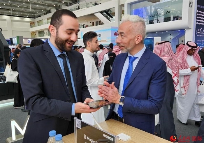 兩名觀眾在榮耀手機展臺前交流。人民網(wǎng)記者 管克江攝