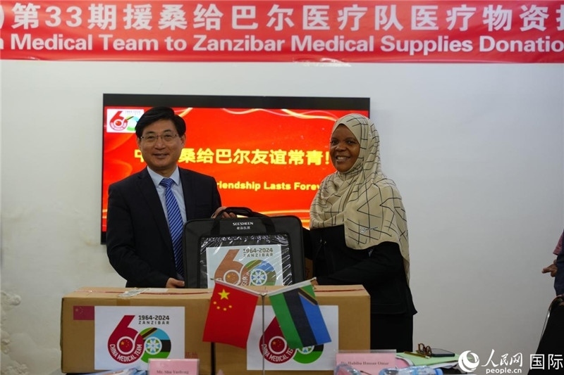江蘇省蘇北人民醫(yī)院黨委書記束余聲捐贈(zèng)物資與桑衛(wèi)生部首席秘書哈比巴。中國(guó)援桑醫(yī)療隊(duì)供圖