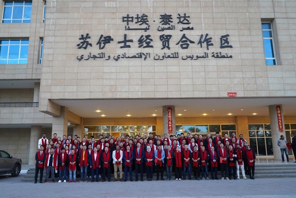 2024年2月11日，在位于埃及蘇伊士省的中?！ぬ┻_(dá)蘇伊士經(jīng)貿(mào)合作區(qū)，中埃員工在合作區(qū)辦公大樓前合影拜年。新華社發(fā)（泰達(dá)合作區(qū)供圖）