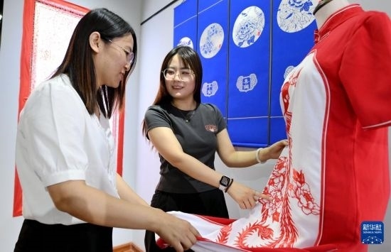 5月31日，在衡水市阜城縣一家剪紙工作室，游客在觀賞帶有剪紙元素的旗袍。