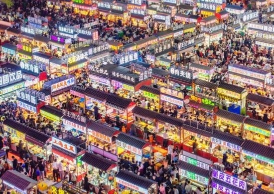 2024年4月21日，人們?cè)诤颖笔≌h小商品夜市品嘗美食（無(wú)人機(jī)照片）。新華社發(fā)（武志偉 攝）