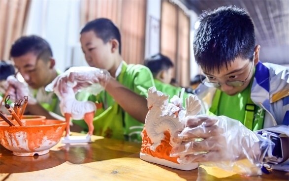 小朋友們?cè)诼尻柺忻辖騾^(qū)朝陽鎮(zhèn)南石山村體驗(yàn)唐三彩素胎施釉技藝。圖片來源:視覺中國