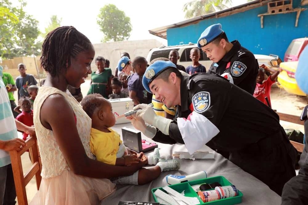 2017年12月28日，在利比里亞蒙羅維亞，中國維和警察防暴隊醫(yī)療人員為兒童做口腔檢查。