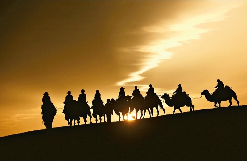 新時代以來，文化和旅游深度融合發(fā)展體制機制不斷健全，成功走出了一條獨具特色的中國旅游發(fā)展之路。圖為2024年9月1日清晨，游客在甘肅省敦煌市鳴沙山月牙泉景區(qū)乘騎駱駝，欣賞大漠風(fēng)光，體驗絲路風(fēng)情。 新華社發(fā) 張曉亮/攝