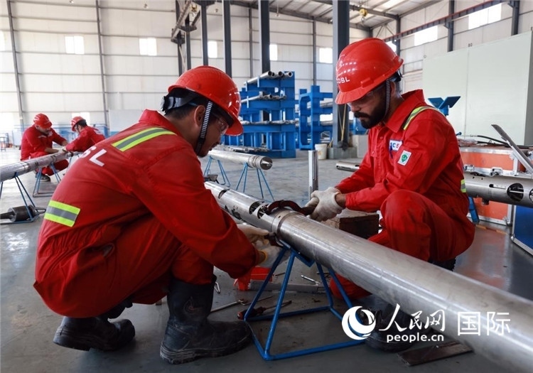 中伊員工共同在檢修鉆井設備。人民網(wǎng)記者管克江攝