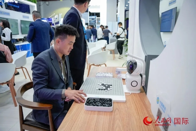 觀眾在中國(guó)移動(dòng)國(guó)際有限公司展臺(tái)體驗(yàn)智慧圍棋機(jī)器人。人民網(wǎng) 塔里克·易卜拉欣攝