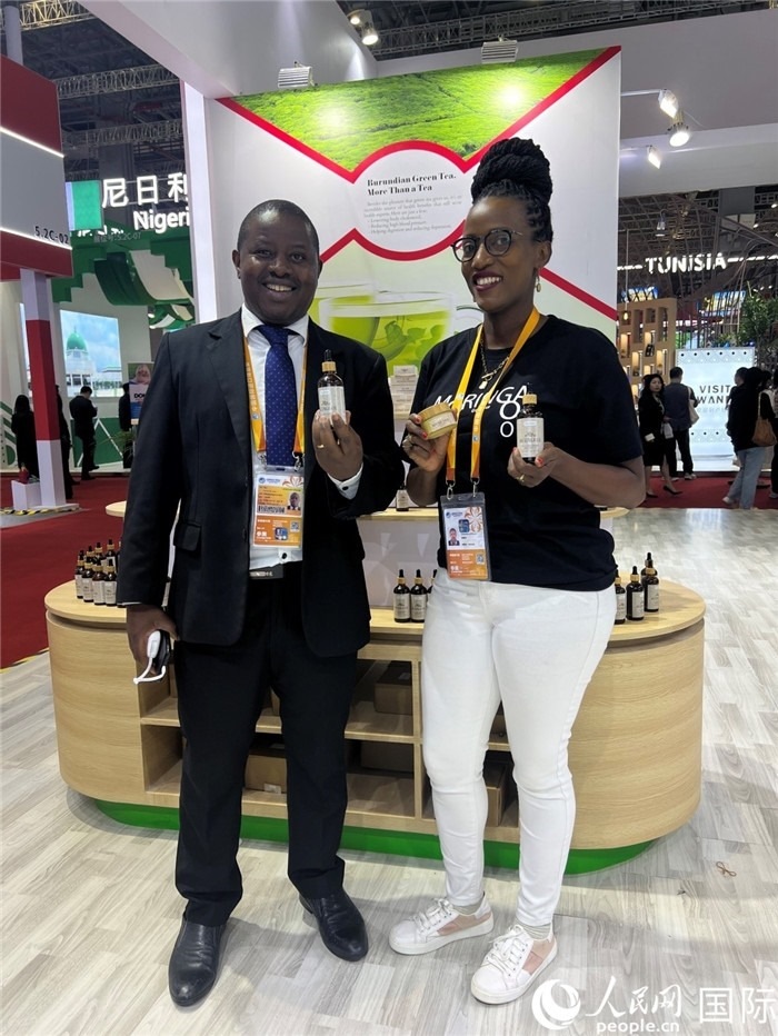 6月6日，布隆迪駐華大使館一等參贊布利馬索·阿爾弗雷德 (左，Bulimaso Alfred) 和參展商卡馬里扎·埃斯特拉 (Kamariza Estella) 在第七屆中國(guó)國(guó)際進(jìn)口博覽會(huì)布隆迪館展示當(dāng)?shù)厣a(chǎn)的辣木油。（人民網(wǎng) 艾里士 攝）