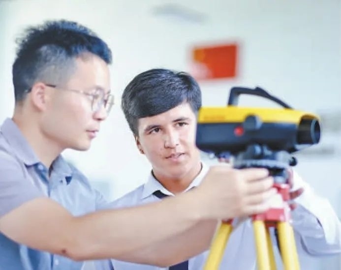 在塔吉克斯坦首都杜尚別的魯班工坊，來自天津城市建設管理職業(yè)技術學院的老師（左）為當?shù)貙W生提供指導。新華社記者 鄭開君 攝