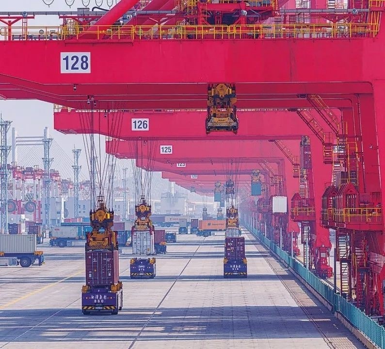 共建“一帶一路”國家在工作制度對接、技術標準協(xié)調(diào)、檢驗結(jié)果互認等方面強化合作、統(tǒng)一標準，貿(mào)易自由化便利化水平不斷提升。上海洋山港海關對接共建國家進出口貨物相關標準，推動通關一體化方式申報，提升通關效率。圖為無人駕駛的全自動導引車在洋山港穿梭往來，搬運集裝箱。王初 攝