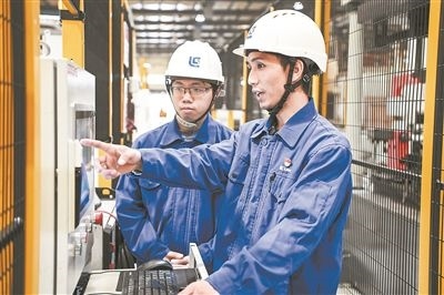 在廣西柳工機(jī)械股份有限公司生產(chǎn)車間內(nèi)，一名高級(jí)技師（右）給徒弟講解數(shù)控設(shè)備操作細(xì)節(jié)。新華社記者 曹祎銘攝