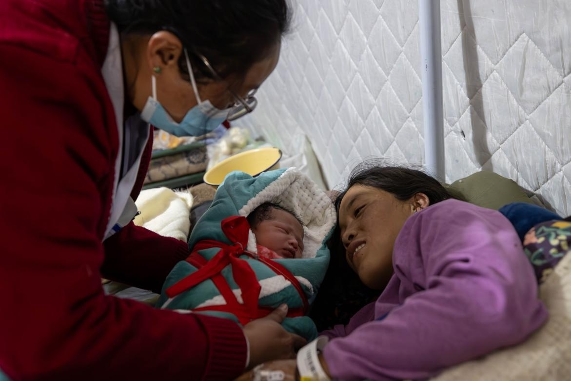 1月10日，定日縣中心醫(yī)院的婦產(chǎn)科醫(yī)生悉心照看一位母親和她懷里的新生兒。人民日?qǐng)?bào)記者張武軍攝