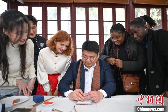 1月20日，篆刻家王臻向外籍留學(xué)生展示篆刻印章。當(dāng)日，來自巴西、馬來西亞、加納、哈薩克斯坦的外籍留學(xué)生在浙江杭州西泠印社體驗(yàn)福貼、春聯(lián)和篆刻，感受古老的中國傳統(tǒng)文化。中新社記者 王剛 攝