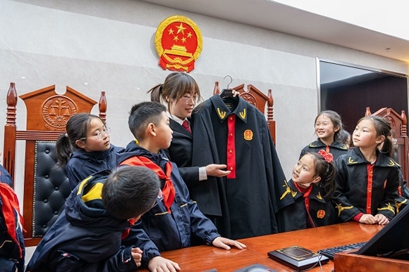 圖②：干警向同學(xué)們介紹法袍。