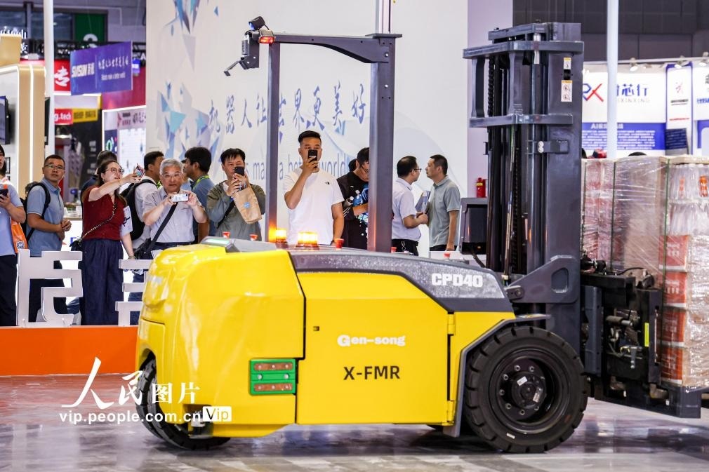 第24屆中國工博會現(xiàn)場，觀眾觀看叉取機器人作業(yè)演示。王初攝（人民圖片網(wǎng)）