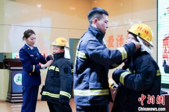圖為學(xué)生們現(xiàn)場穿戴消防頭盔和戰(zhàn)斗服。中新社記者 趙宇航 攝