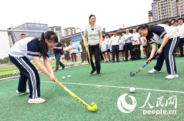 陳朝霞（中）指導學生體驗曲棍球。 人民網(wǎng)記者 楊磊攝