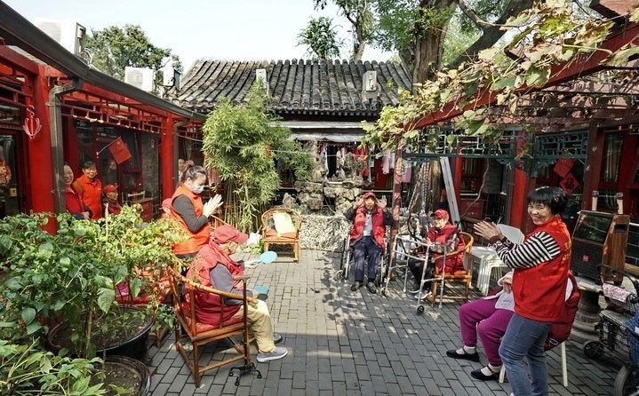 2024年10月12日，鐘樓灣胡同的老年人在社區(qū)內(nèi)的四合院養(yǎng)老驛站休閑。2017年起，北京市先后開(kāi)展了兩輪背街小巷環(huán)境整治提升行動(dòng)，完整保留了中軸線生活建筑群的歷史信息，并根據(jù)居民的生活和居住方式進(jìn)行適配化的更新和改造，極大地改善了生活環(huán)境。2023年鐘樓灣胡同被評(píng)為“北京最美街巷”。