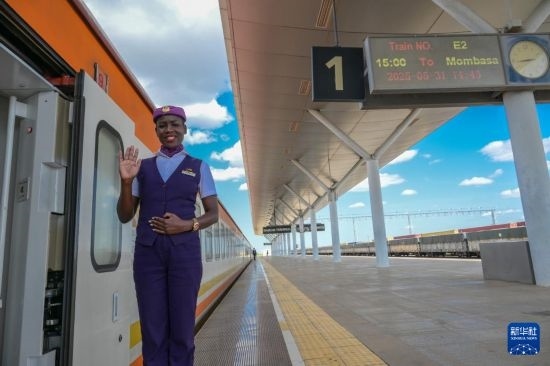 5月31日，在蒙內(nèi)鐵路內(nèi)羅畢站，一名乘務(wù)員在即將開往蒙巴薩的E2次列車旁等候乘客。新華社記者 楊光 攝