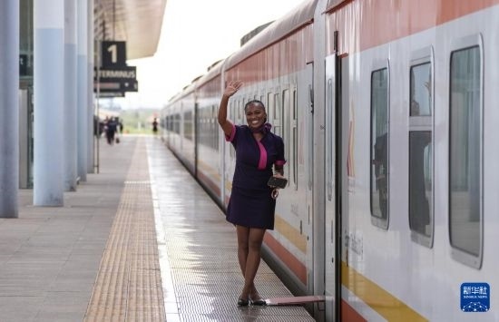 5月31日，在蒙內(nèi)鐵路內(nèi)羅畢站，一名乘務(wù)員在即將開往蒙巴薩的E2次列車旁等候乘客。新華社記者 李亞輝 攝